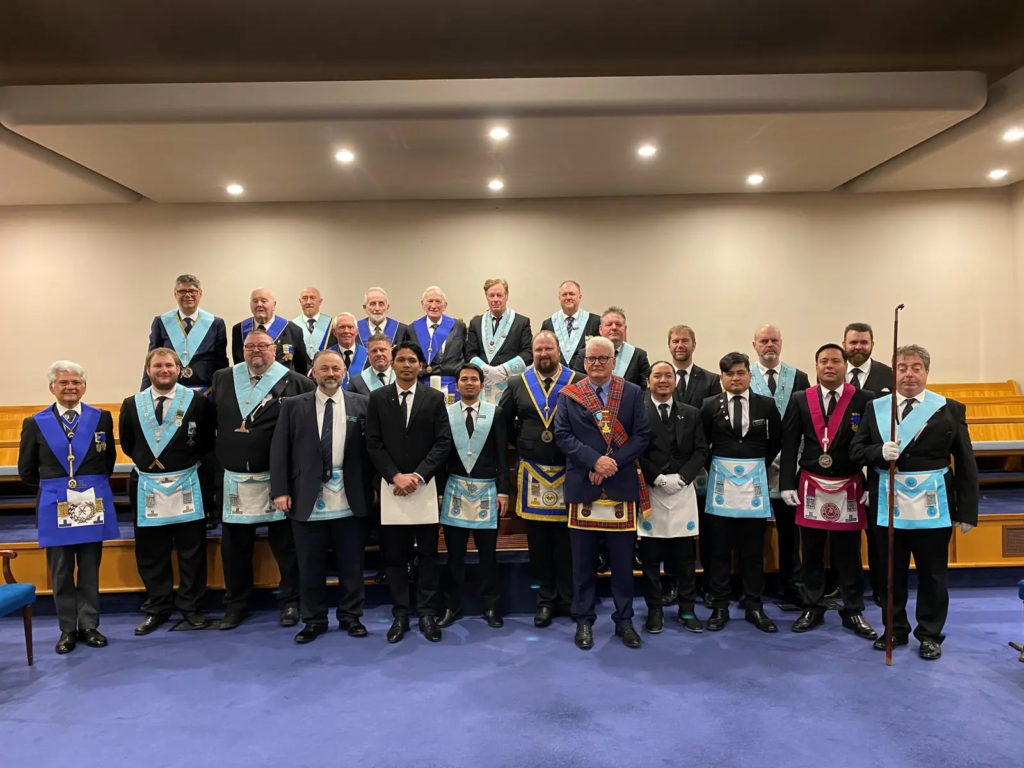 Freemasons gathered in regalia inside the lodge room.